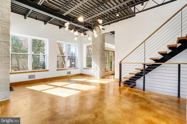 entryway featuring a high ceiling, concrete floors, visible vents, baseboards, and stairway