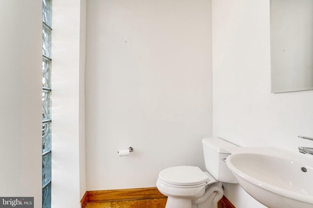 bathroom featuring toilet, baseboards, and a sink