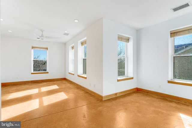 spare room with visible vents, plenty of natural light, finished concrete flooring, and baseboards