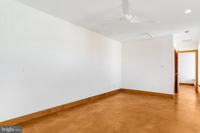 unfurnished room featuring finished concrete flooring, attic access, visible vents, baseboards, and ceiling fan