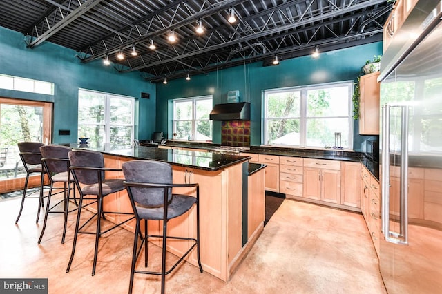 kitchen with a breakfast bar, concrete floors, a kitchen island, exhaust hood, and light brown cabinetry