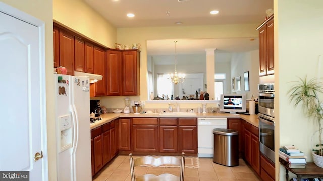 kitchen featuring pendant lighting, white appliances, light tile patterned floors, and a notable chandelier