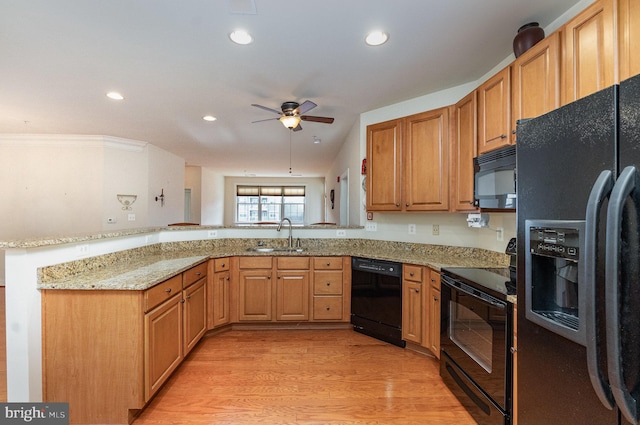 kitchen with sink, light stone counters, light wood-type flooring, kitchen peninsula, and black appliances