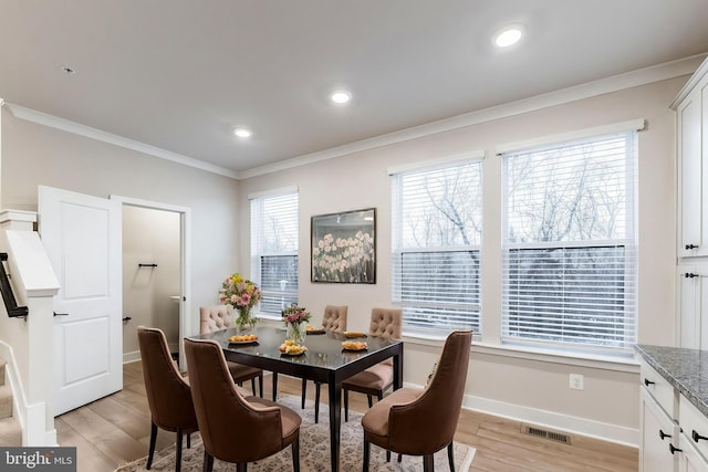 dining area with crown molding and light hardwood / wood-style floors