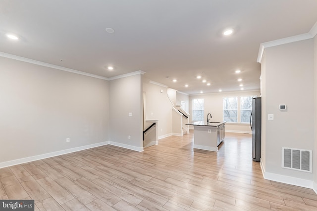 spare room featuring sink, ornamental molding, and light wood-type flooring