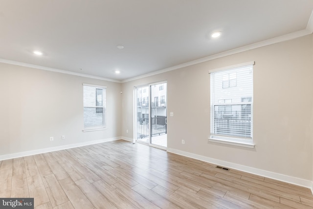 unfurnished room featuring a wealth of natural light, ornamental molding, and light wood-type flooring