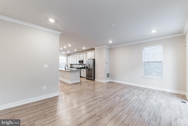 unfurnished living room featuring ornamental molding, sink, and light hardwood / wood-style flooring