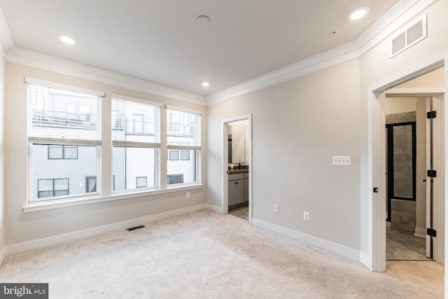 unfurnished bedroom featuring crown molding, light carpet, and ensuite bath