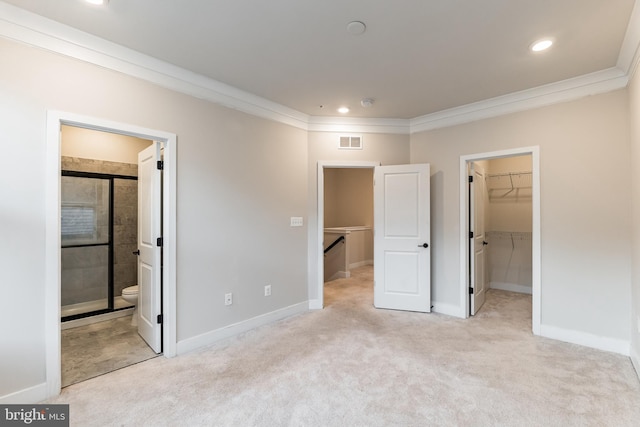 unfurnished bedroom with connected bathroom, a walk in closet, light colored carpet, crown molding, and a closet