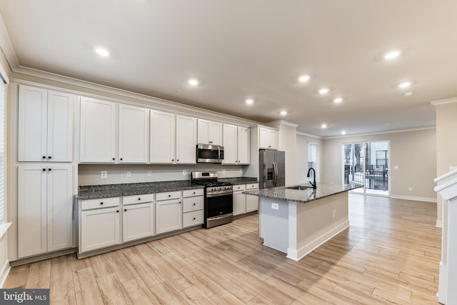 kitchen with stainless steel appliances, light hardwood / wood-style floors, a center island with sink, and white cabinets