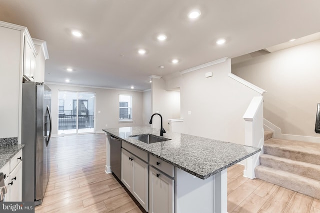 kitchen with sink, stainless steel appliances, an island with sink, and white cabinets