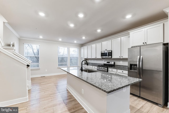 kitchen featuring sink, stainless steel appliances, white cabinets, and a center island with sink