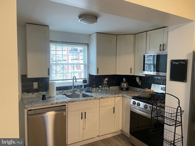 kitchen featuring sink, light wood-type flooring, appliances with stainless steel finishes, light stone countertops, and white cabinets