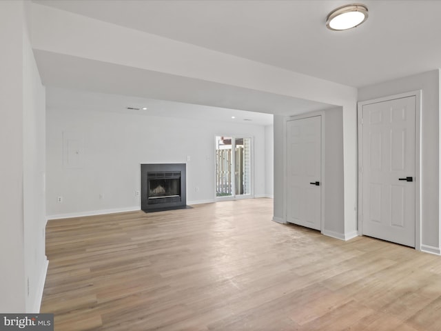 unfurnished living room with electric panel and light hardwood / wood-style floors