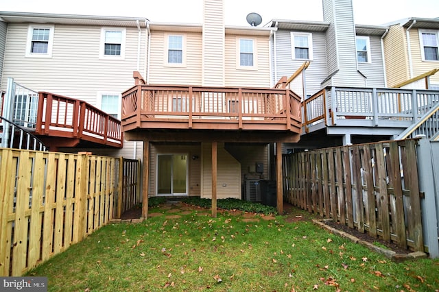 rear view of property featuring a lawn, cooling unit, and a deck