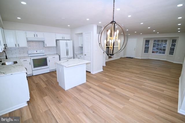 kitchen featuring white appliances, a center island, decorative light fixtures, white cabinetry, and tasteful backsplash