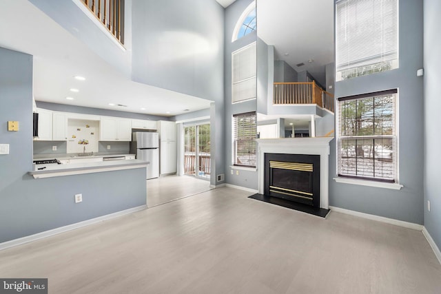 unfurnished living room featuring sink, plenty of natural light, and a towering ceiling