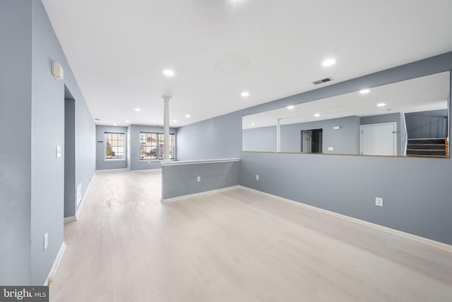 empty room with decorative columns and light wood-type flooring