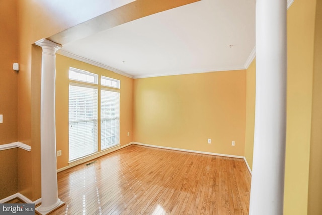 empty room with light wood finished floors, decorative columns, visible vents, baseboards, and ornamental molding