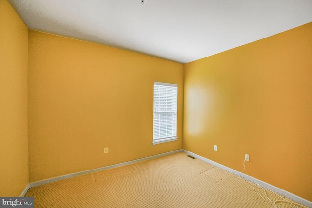 spare room with light carpet, visible vents, and baseboards