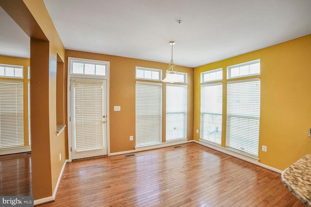 interior space with baseboards, visible vents, and hardwood / wood-style floors