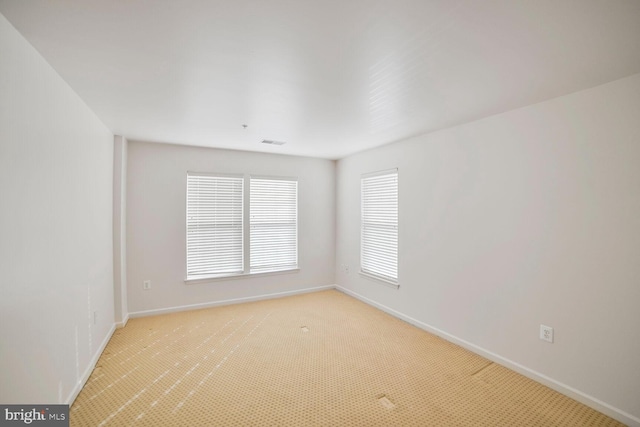 unfurnished room with visible vents, light carpet, and baseboards