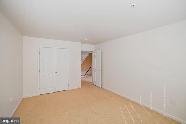 unfurnished bedroom with baseboards, a closet, and light colored carpet