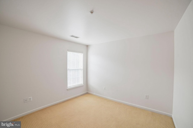 spare room with light colored carpet, visible vents, and baseboards