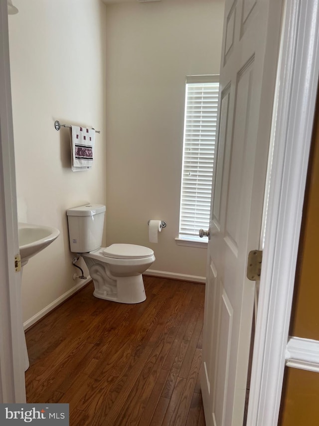 half bathroom featuring toilet, baseboards, and wood finished floors