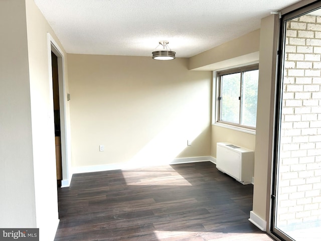 unfurnished room featuring radiator heating unit, a textured ceiling, and dark hardwood / wood-style flooring