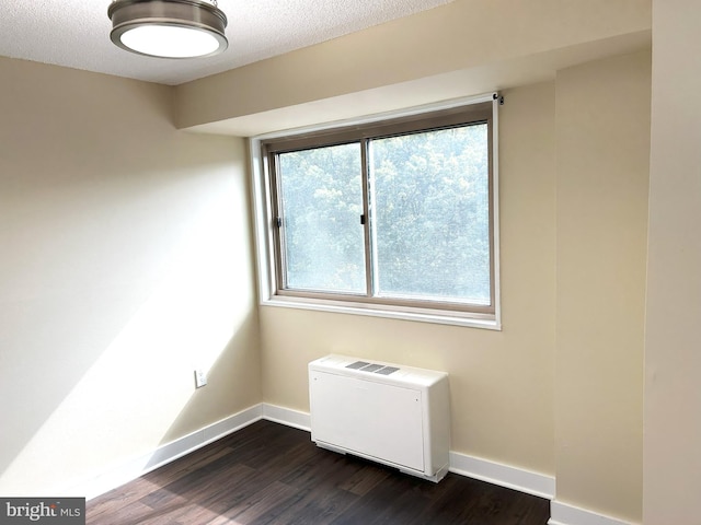 empty room featuring a textured ceiling and dark hardwood / wood-style flooring