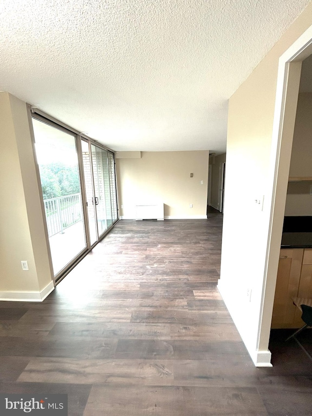 spare room with floor to ceiling windows, a textured ceiling, and dark hardwood / wood-style floors