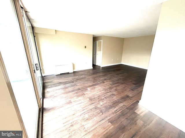 spare room featuring dark hardwood / wood-style floors and radiator