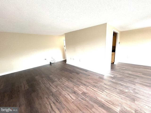 empty room with a textured ceiling and dark hardwood / wood-style flooring