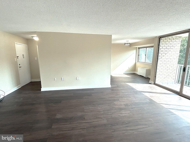 empty room with radiator heating unit, a textured ceiling, and dark hardwood / wood-style flooring