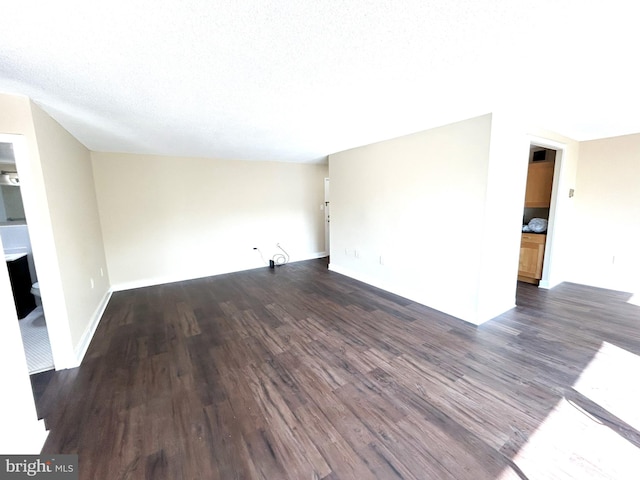 spare room with a textured ceiling and dark hardwood / wood-style flooring