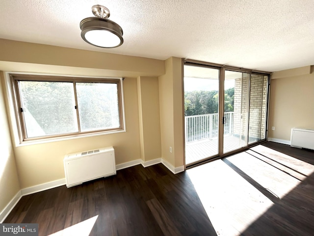 empty room featuring radiator heating unit, a textured ceiling, and dark hardwood / wood-style floors