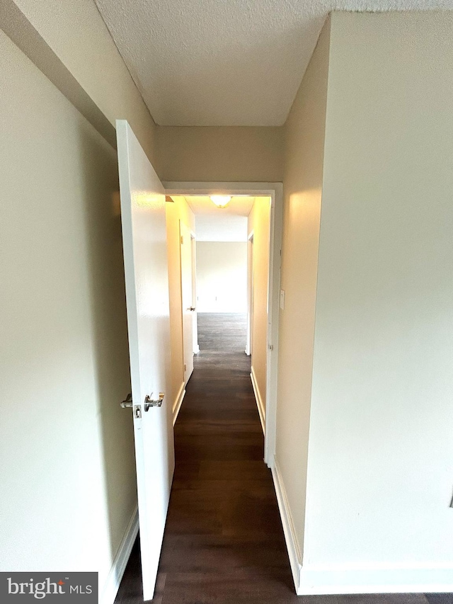 corridor with dark wood-type flooring and a textured ceiling