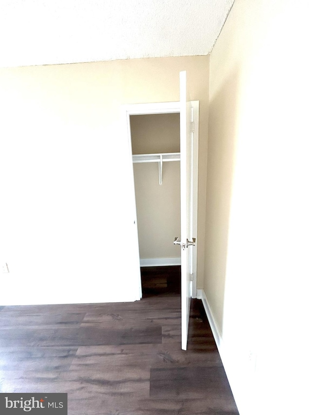 unfurnished bedroom featuring a textured ceiling, dark hardwood / wood-style flooring, and a closet