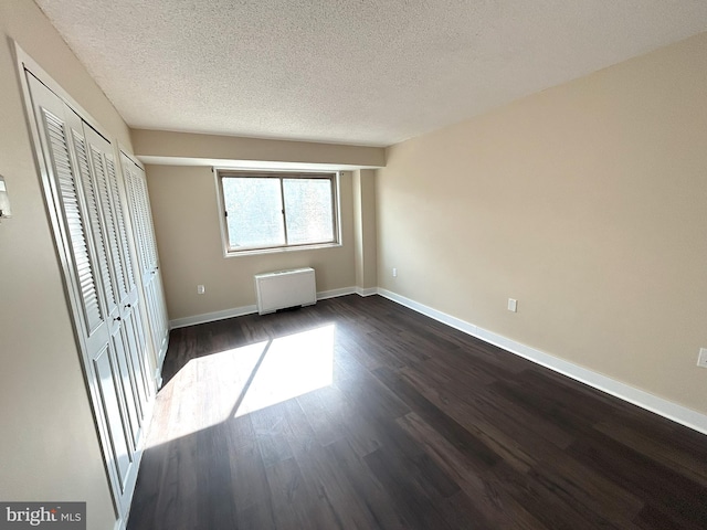 unfurnished bedroom featuring a textured ceiling, radiator, and dark hardwood / wood-style flooring