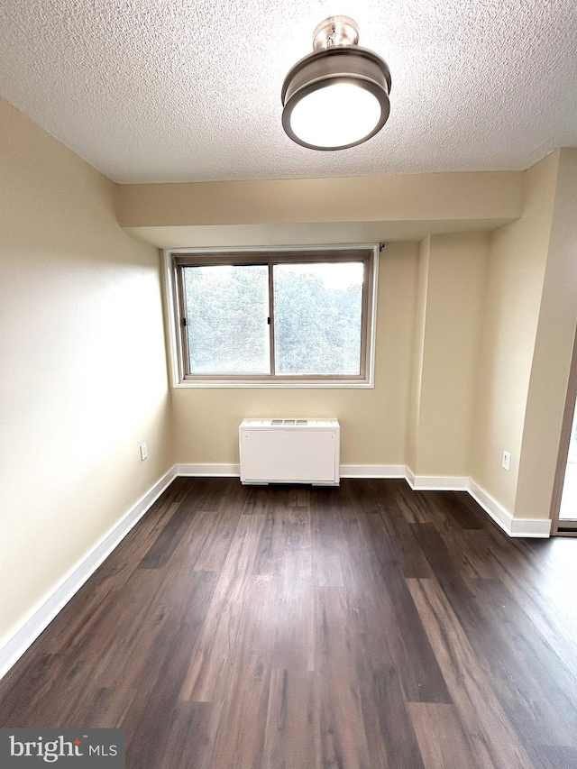 empty room featuring a textured ceiling, dark hardwood / wood-style floors, and radiator