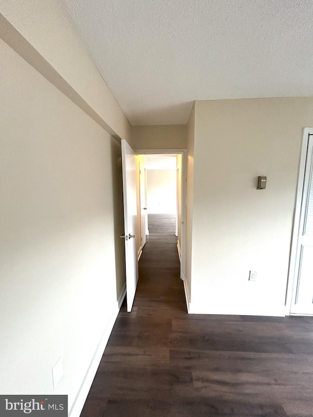 hall with a textured ceiling and dark hardwood / wood-style flooring