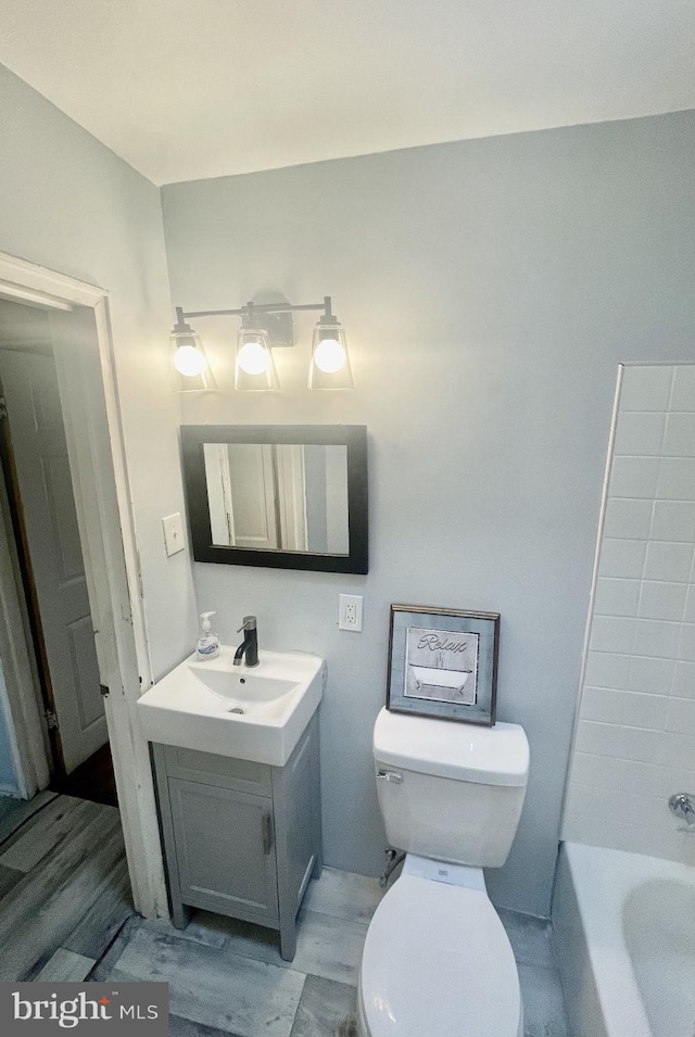 bathroom with vanity, a bathtub, and toilet