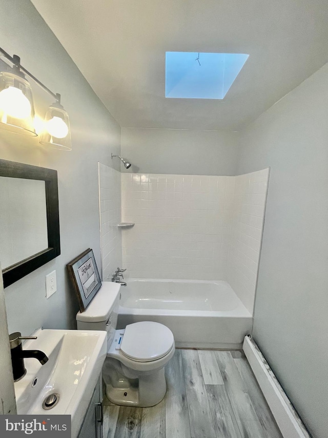 full bathroom with hardwood / wood-style floors, a skylight, vanity, toilet, and washtub / shower combination