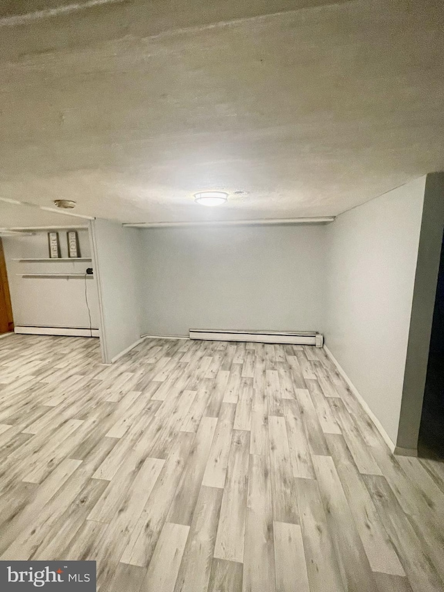 basement featuring a baseboard radiator and light hardwood / wood-style floors