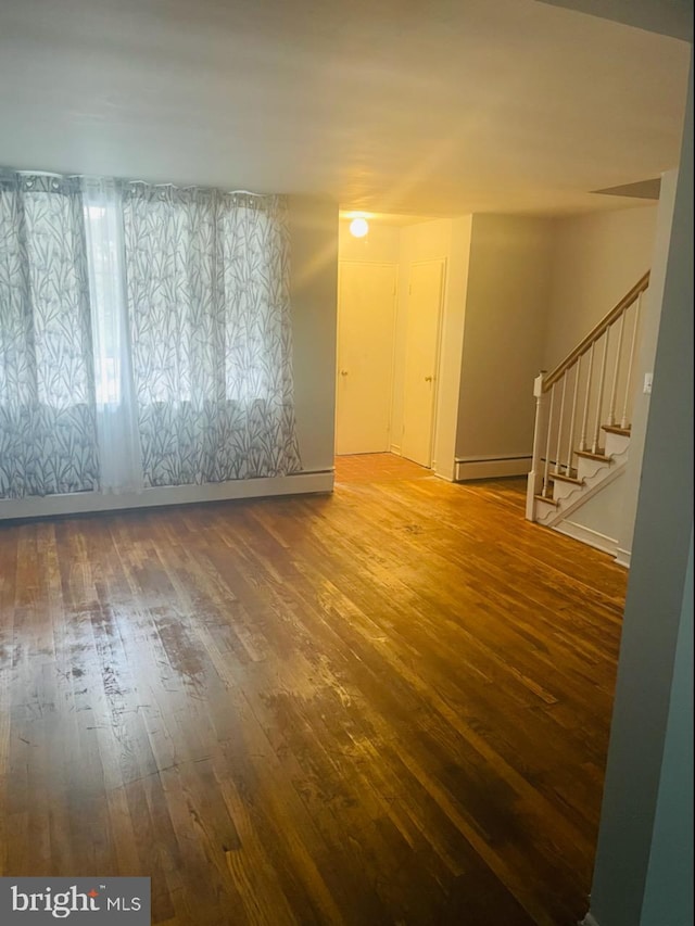 empty room featuring baseboard heating and hardwood / wood-style floors