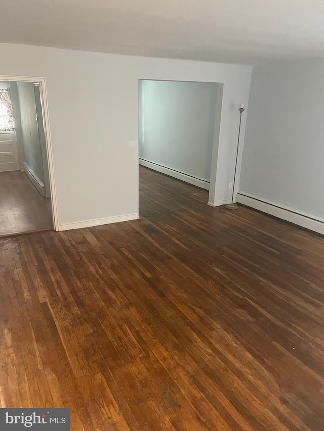 spare room with dark wood-type flooring and a baseboard radiator