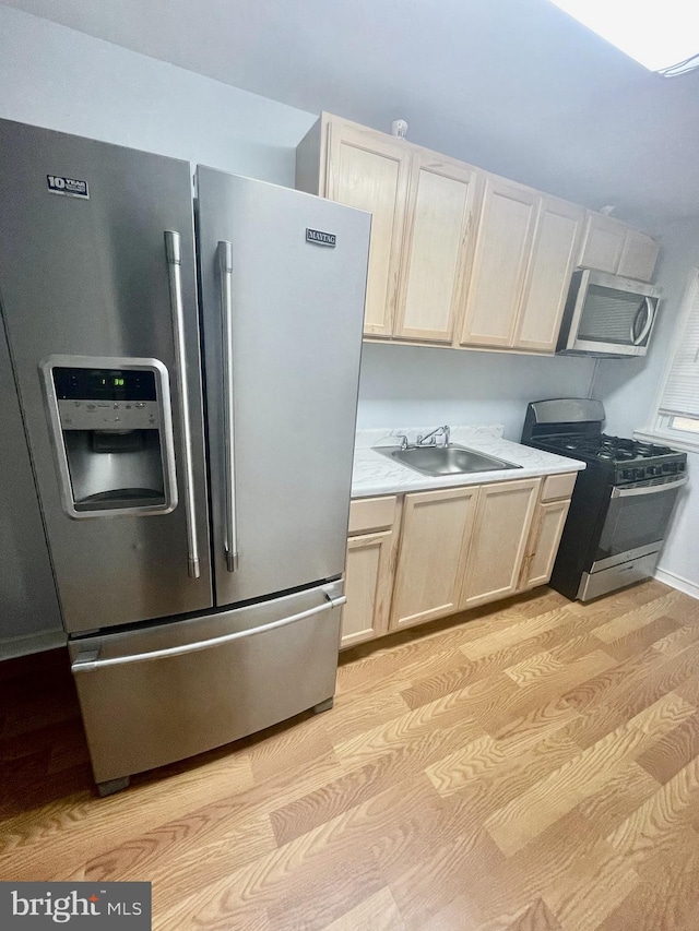 kitchen featuring appliances with stainless steel finishes, sink, and light hardwood / wood-style flooring