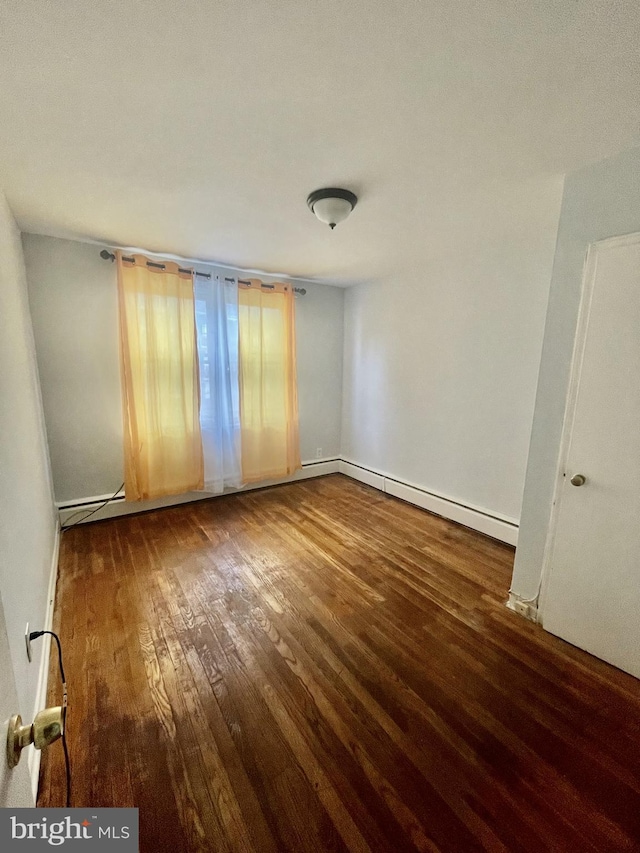 empty room featuring a baseboard radiator and dark hardwood / wood-style floors