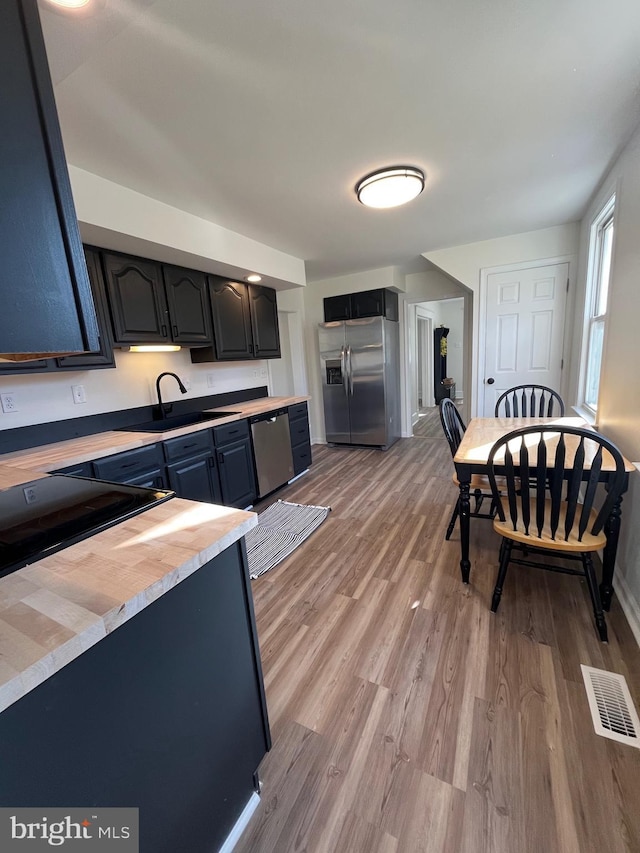 kitchen with stainless steel appliances, sink, and light hardwood / wood-style floors